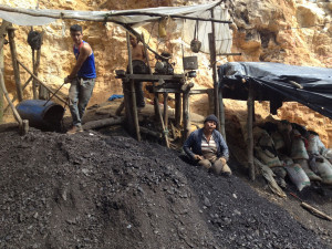 Coal mine. Seven guys down 300 feet. Three at the top operating a winch powered by a motorcycle engine pulling up a blue plastic garbage can. The woman is sorting bigger chunks from a pile. Tough way to make a living!  Competing with big mechanized industry elsewhere...